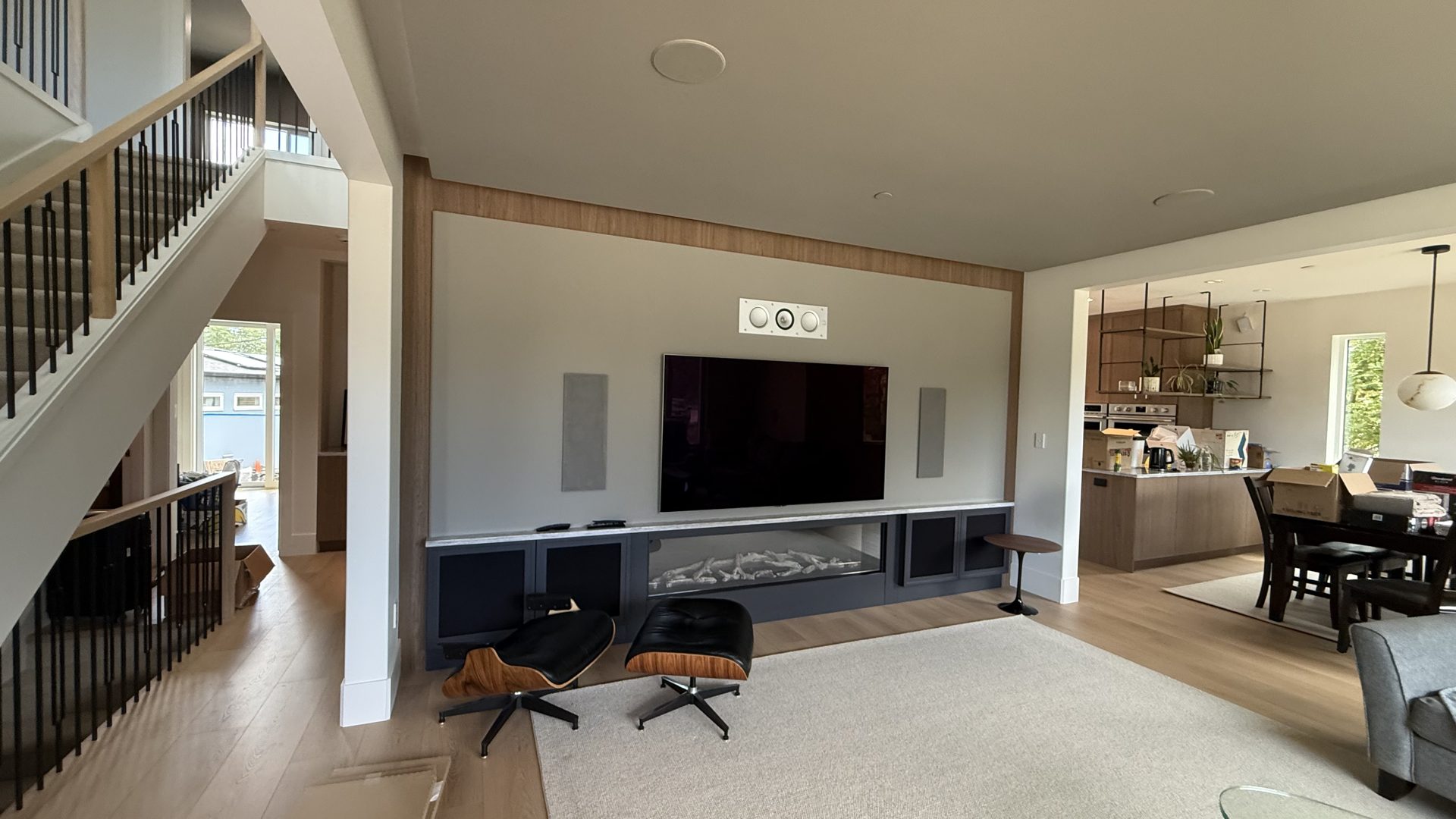 Open living room with a media wall, linear fireplace and wide-plank floors