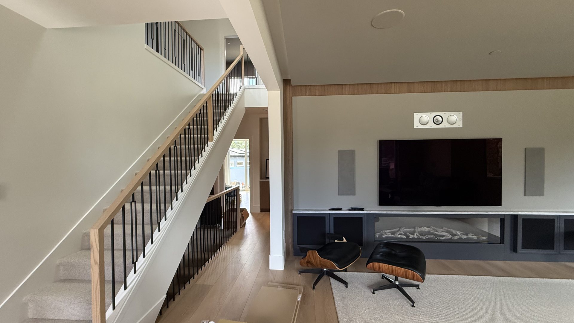 New staircase with wood handrail and black balusters rising to the second storey